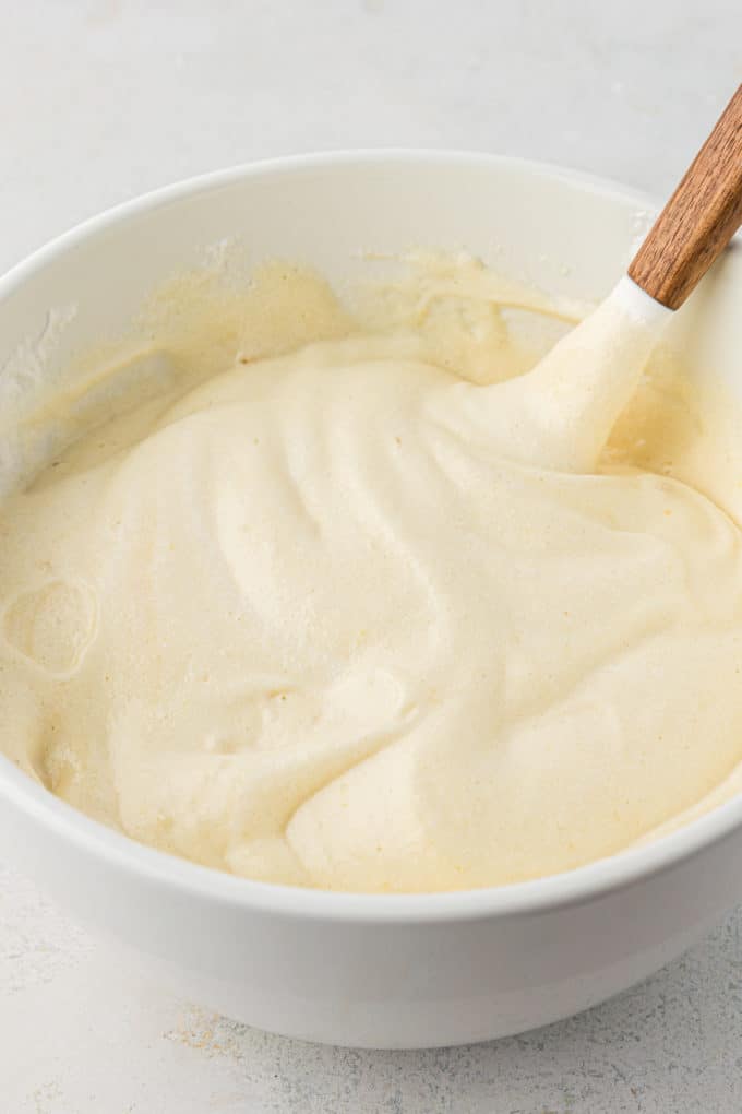 tres leches cake batter in a white bowl with a wooden spatula