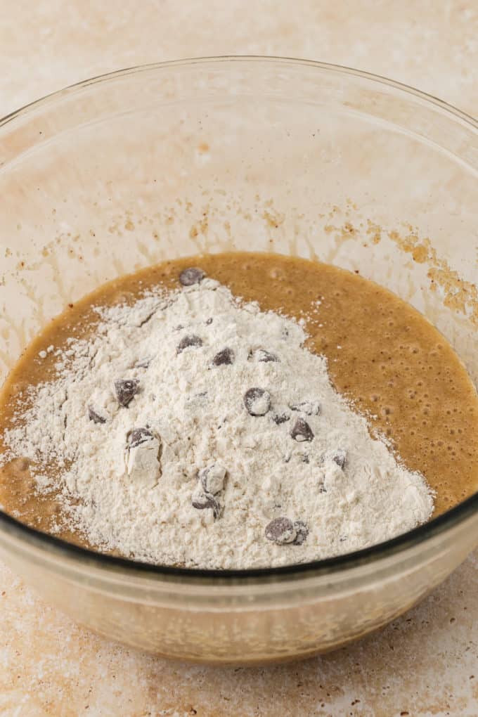wet ingredients for cookies in a clear glass bowl with the dry ingredients in a mound on top not mixed in yet