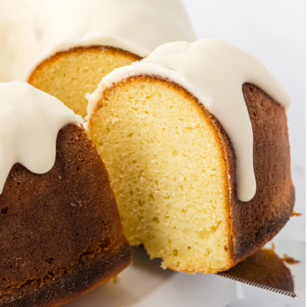 a slice of vanilla bundt cake being lifted by a spatula away from the rest of the cake