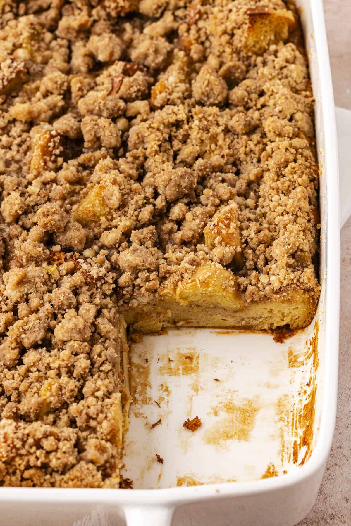 close up of a white baking dish full of french toast casserole missing one slice