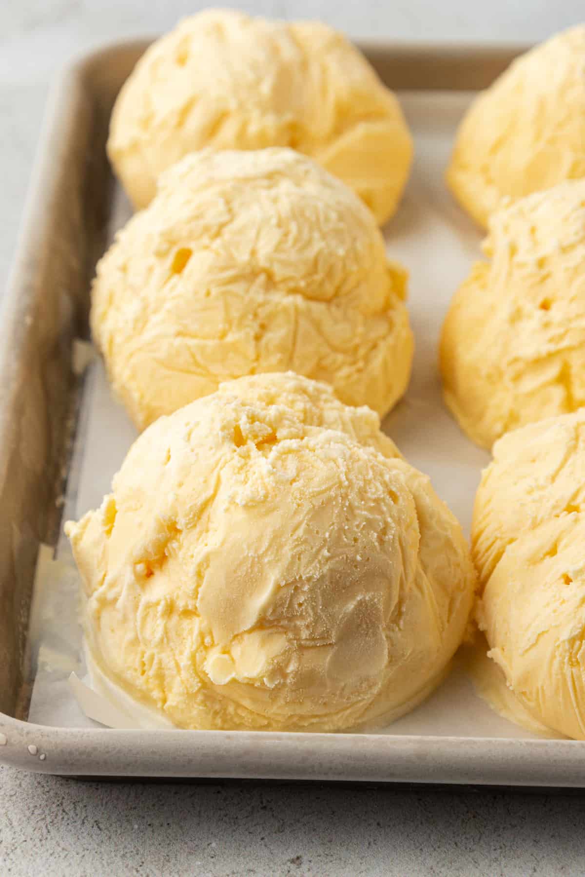 balls of vanilla ice cream on a sheet pan in rows
