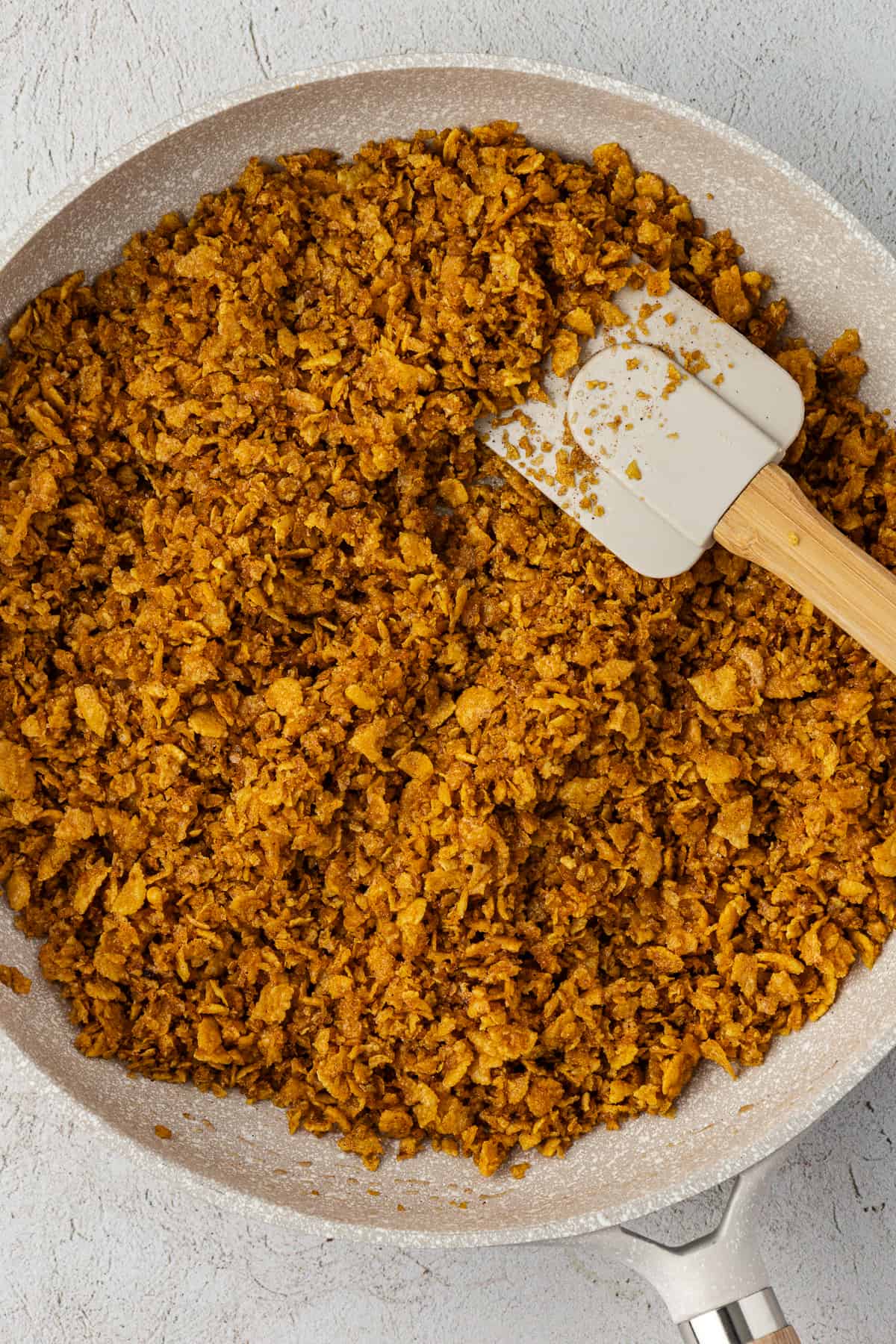 a corn flake cereal mixture in a pan with a spatula