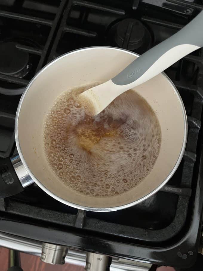 browned butter being stirred with a spatula in a small pot on a stovetop