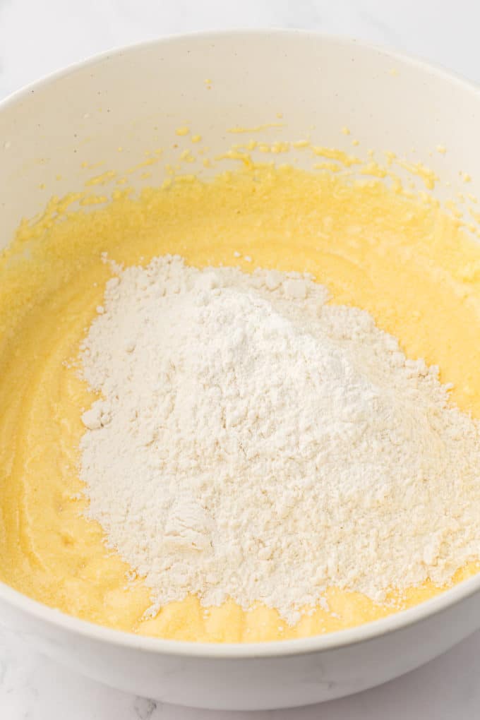 wet ingredients for bundt cake in a white bowl with dry ingredients on top that haven't been mixed in yet