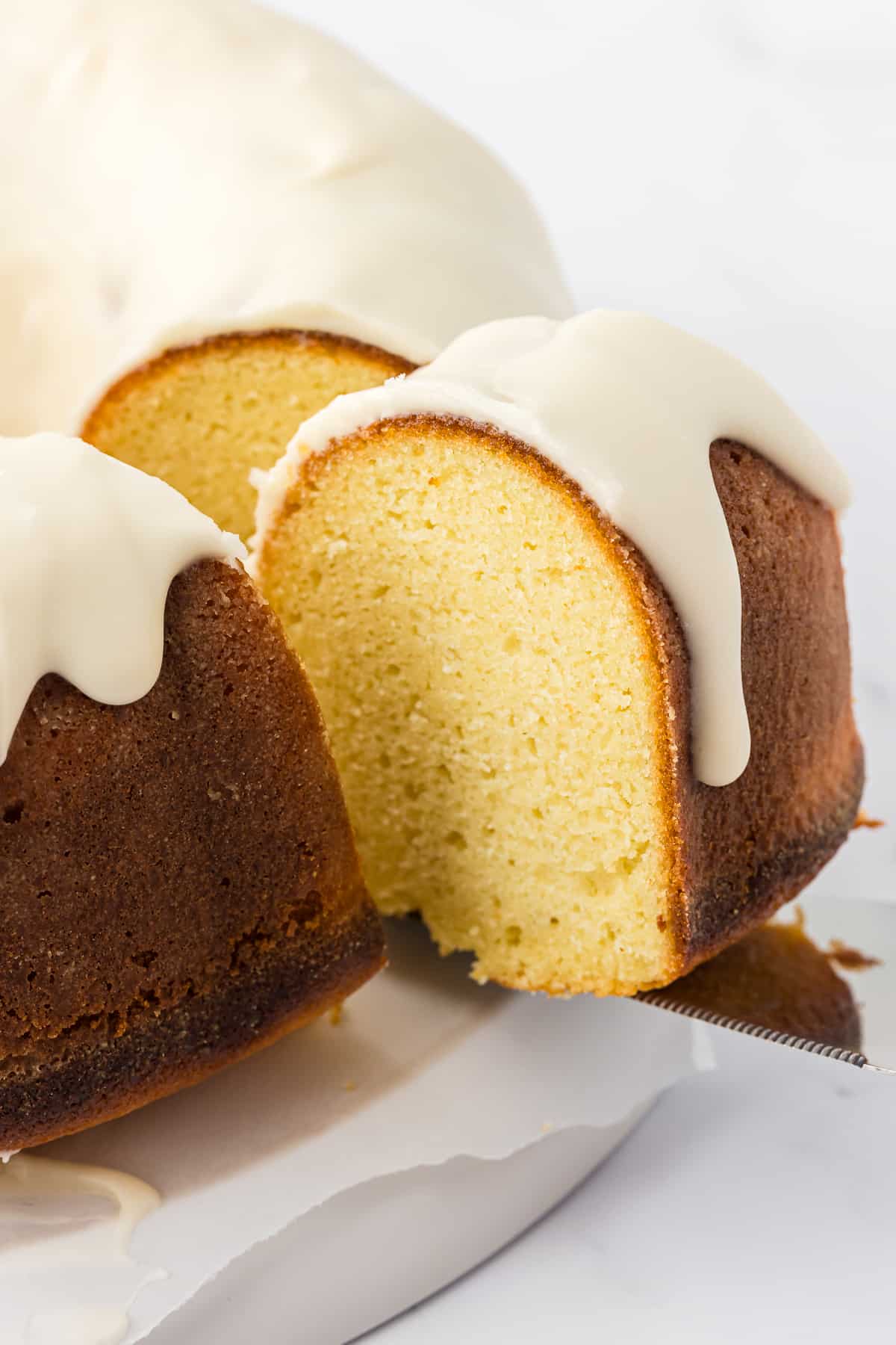 a slice of vanilla bundt cake being lifted away from the rest of the cake with a spatula