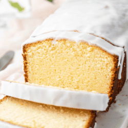 cream cheese pound cake with three slices cut on a white cutting board