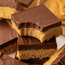 a stack of peanut butter bars with a bite out of the top bar and more bars scattered all around
