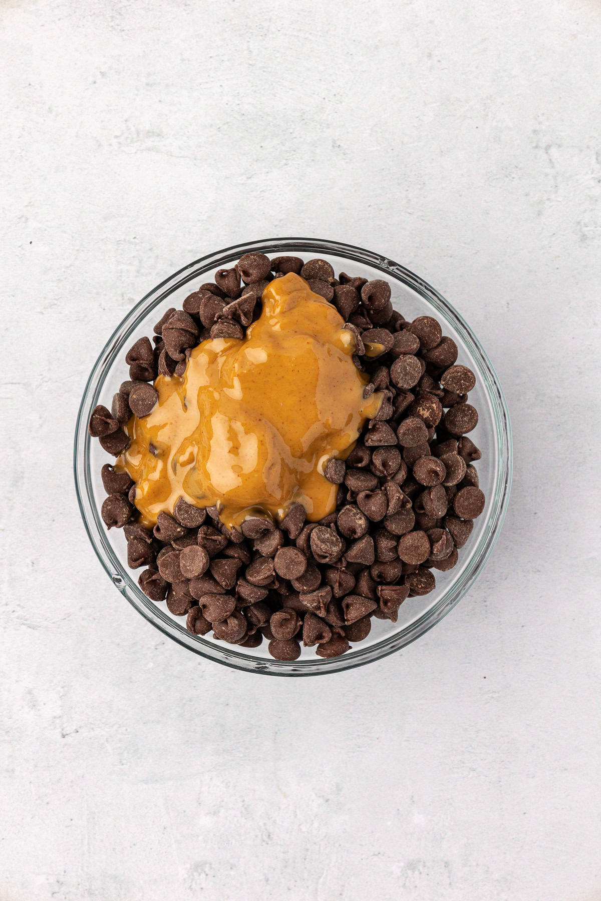 chocolate chips and creamy peanut butter in a clear glass bowl