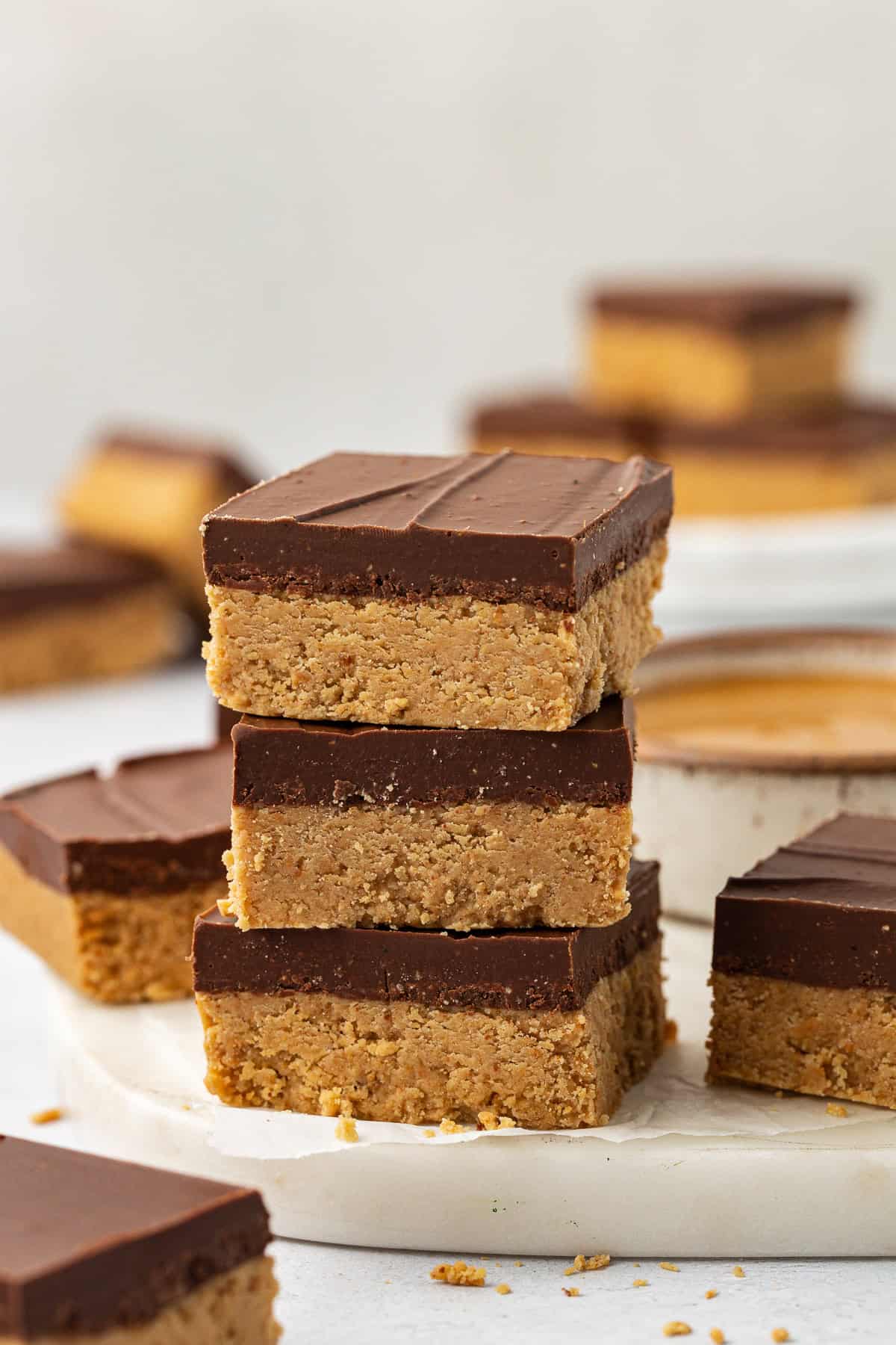 a stack of three peanut butter bars with more bars scattered all around and in the background