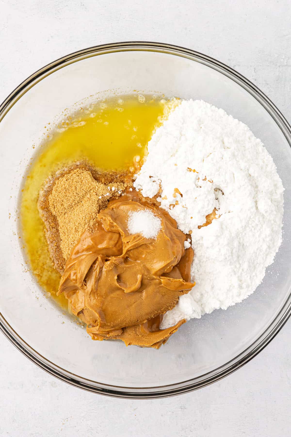 melted butter, powdered sugar, graham cracker crumbs and creamy peanut butter in a clear glass bowl