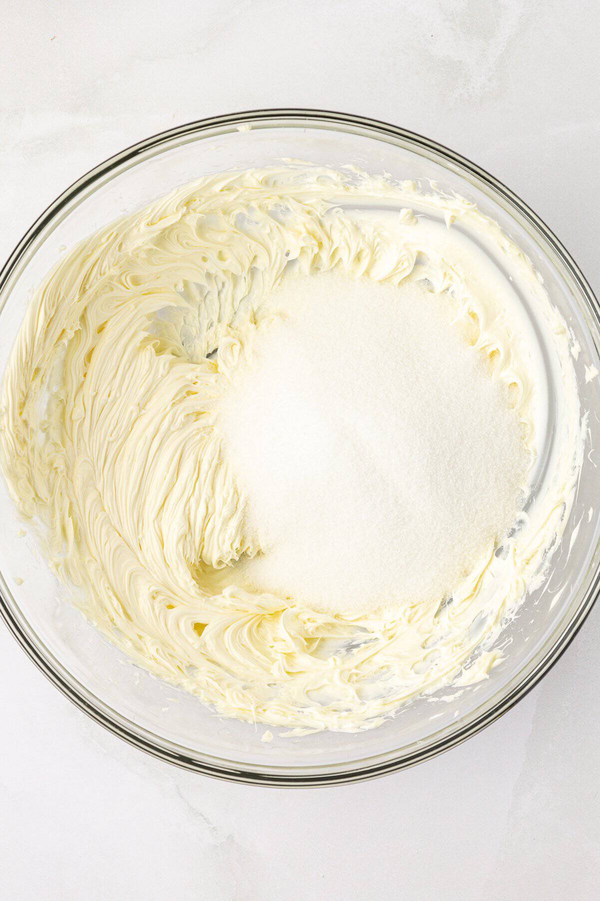 butter creamed in a clear glass bowl with granulated sugar on top
