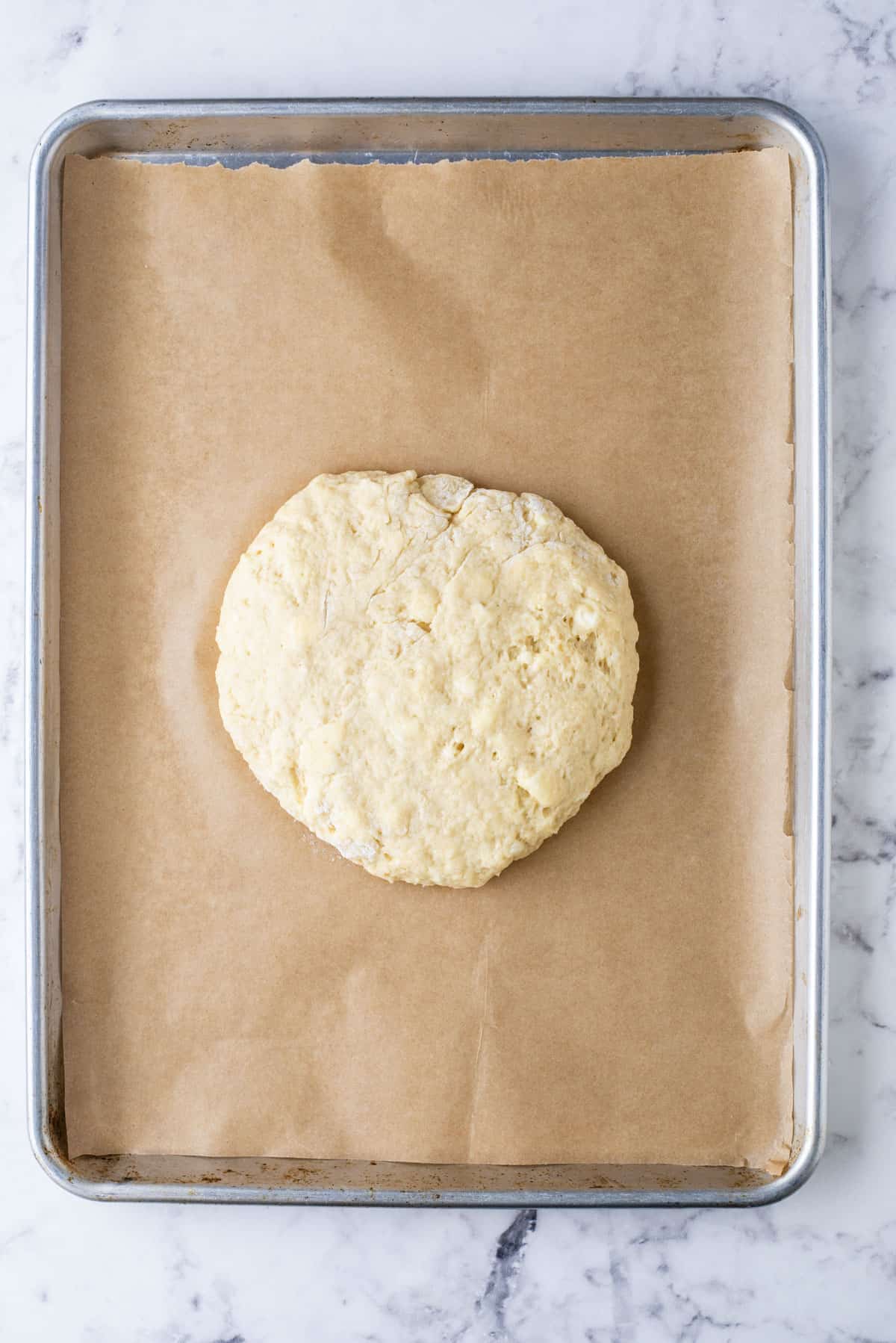 a round disc of scone dough on a baking sheet lined with parchment paper
