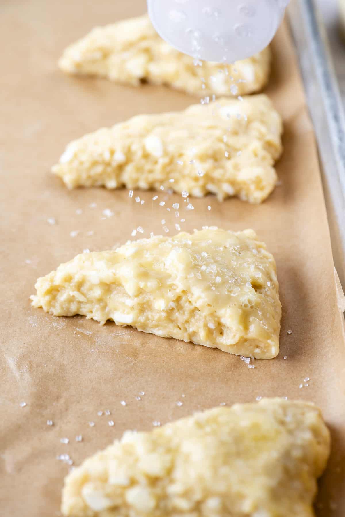 sprinkling scones with coarse salt on a baking sheet lined with parchment paper