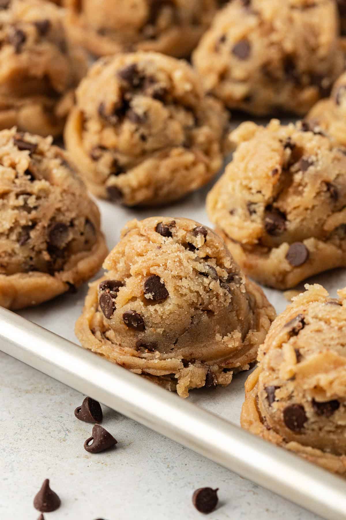 chocolate chip cookie dough balls in rows on a baking sheet