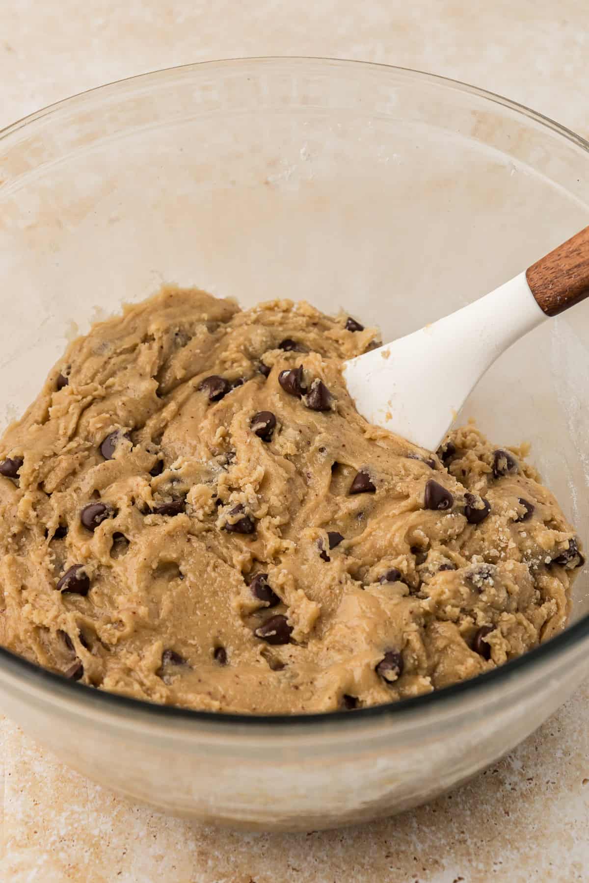 a glass bowl with pizookie batter in it and a spatula