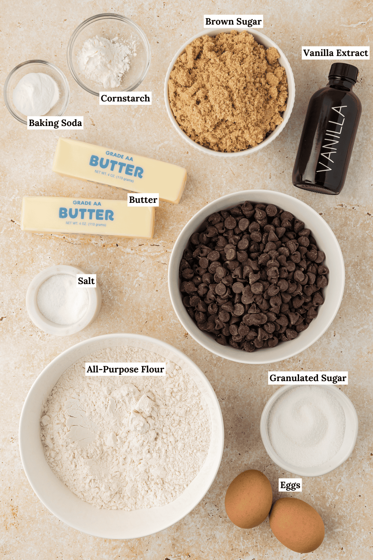 Overhead view of ingredients for pizookie including baking soda, cornstarch, brown sugar, vanilla extra, butter, chocolate chips, salt, all-purpose flour, granulated sugar and eggs