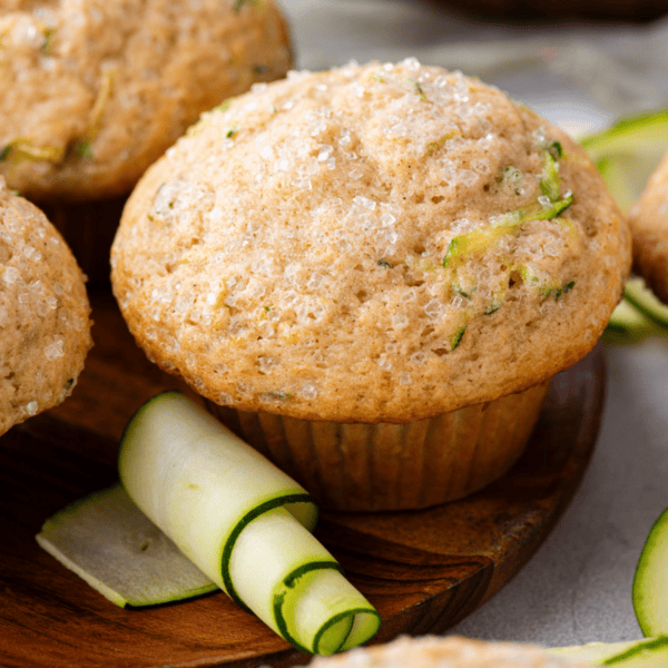 zucchini muffins on a wood plate with a rolled zucchini peel