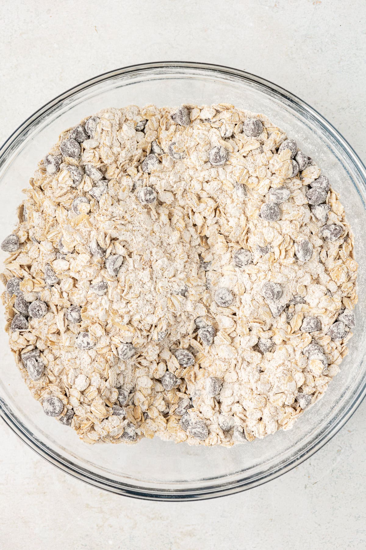 oats, flour mixture and chocolate chips mixed in a clear glass bowl
