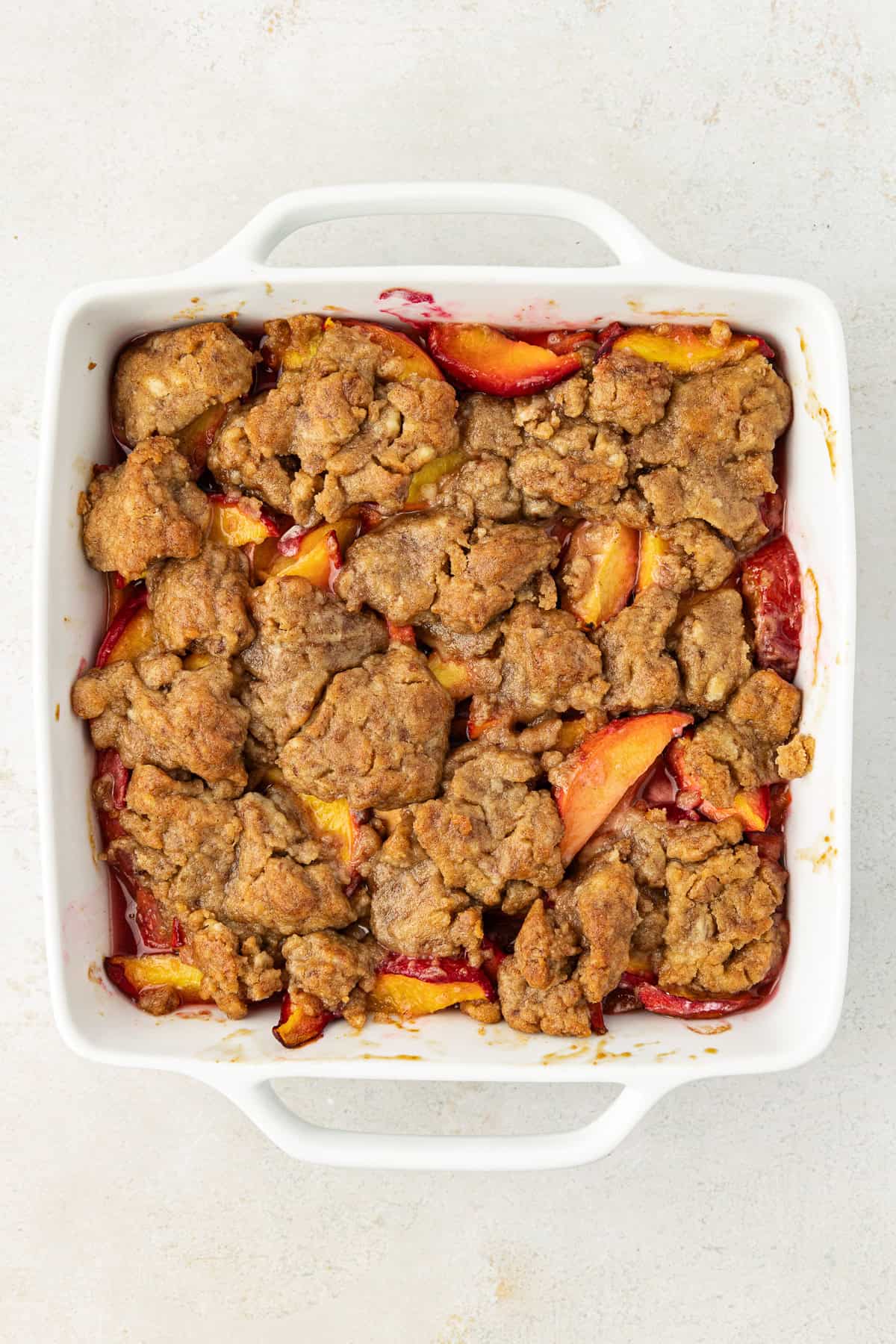 over head view of peach cobbler baked in a square white baking dish