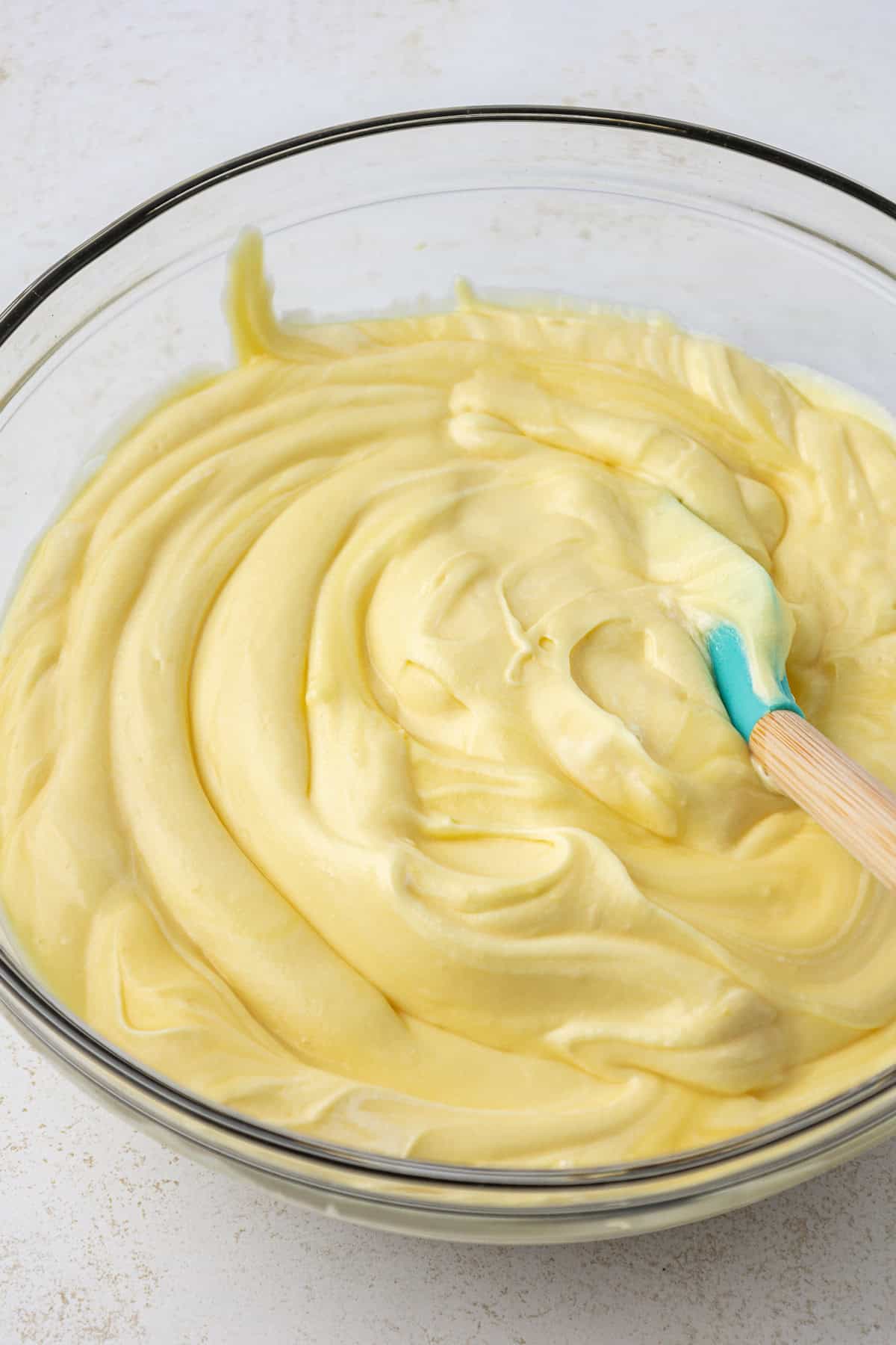 ingredients for dirt cake pudding layer in a large clear glass bowl with a spatula