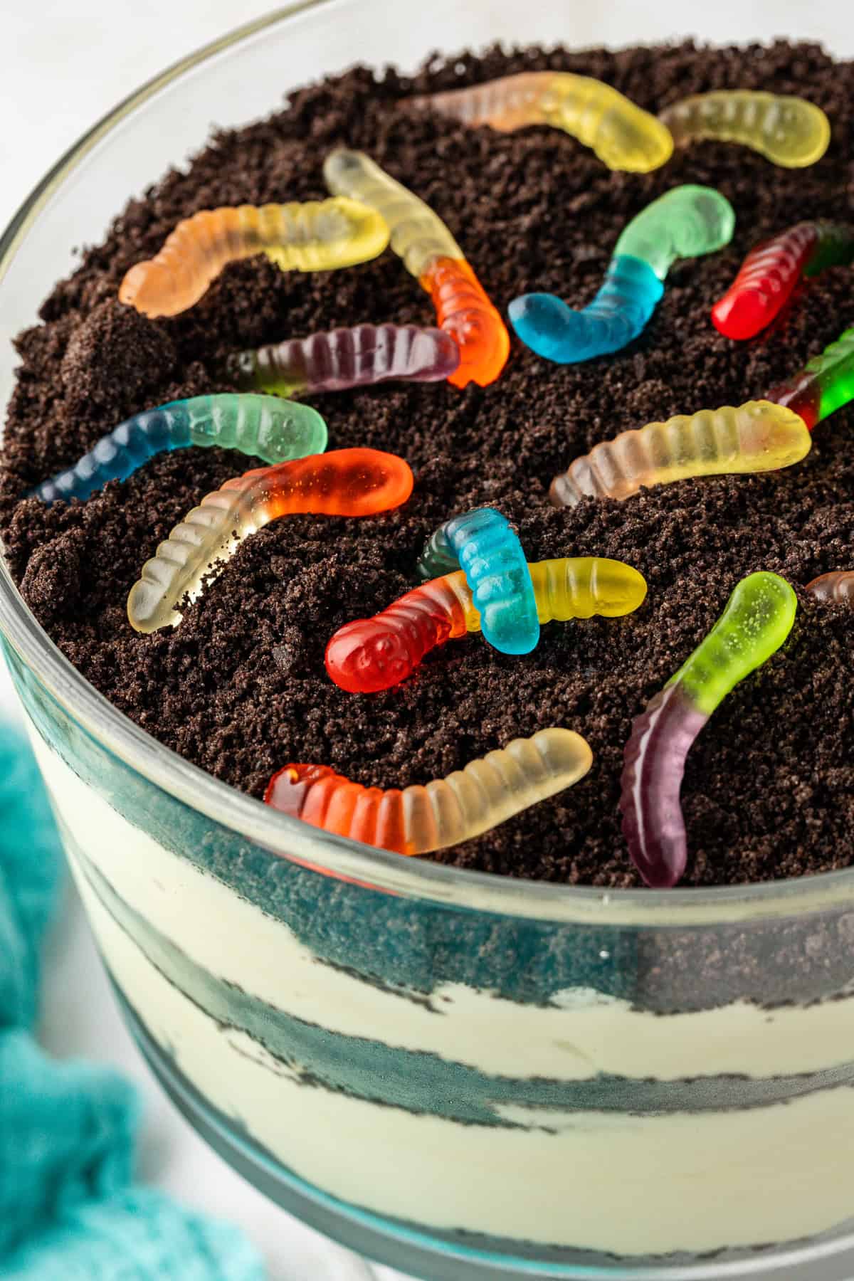 close up of a large trifle bowl of dirt cake topped with crushed oreos and gummy worms