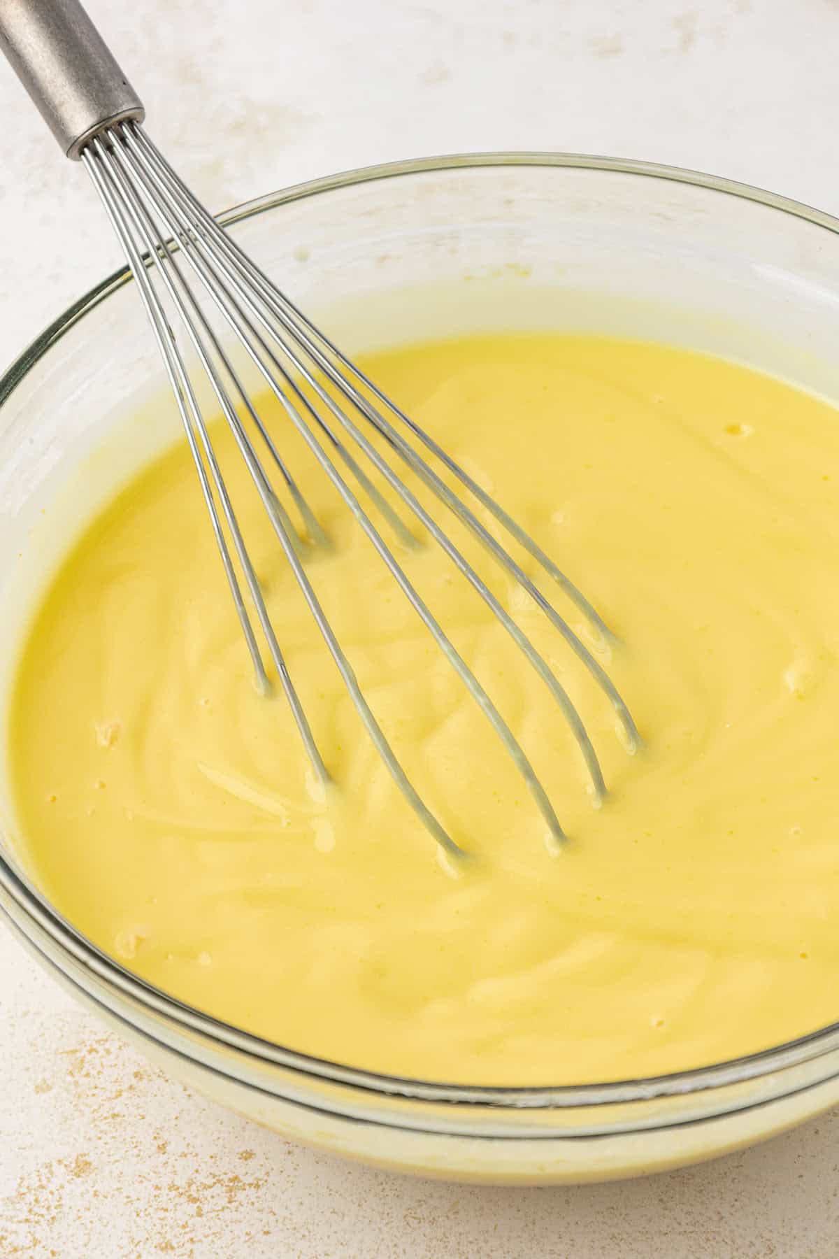 instant vanilla pudding mixed in a clear glass bowl with a whisk