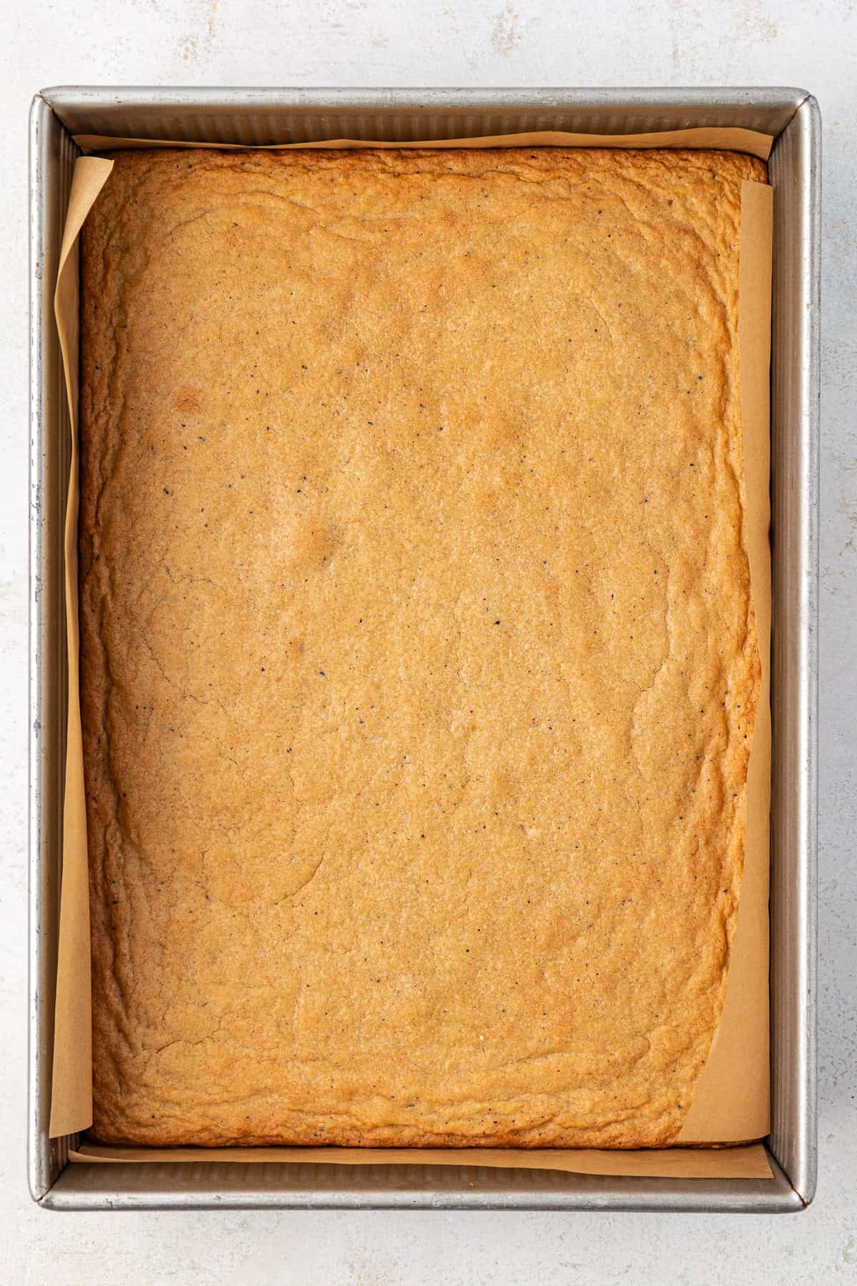 a metal pan lined with parchment paper with freshly baked blondies in it