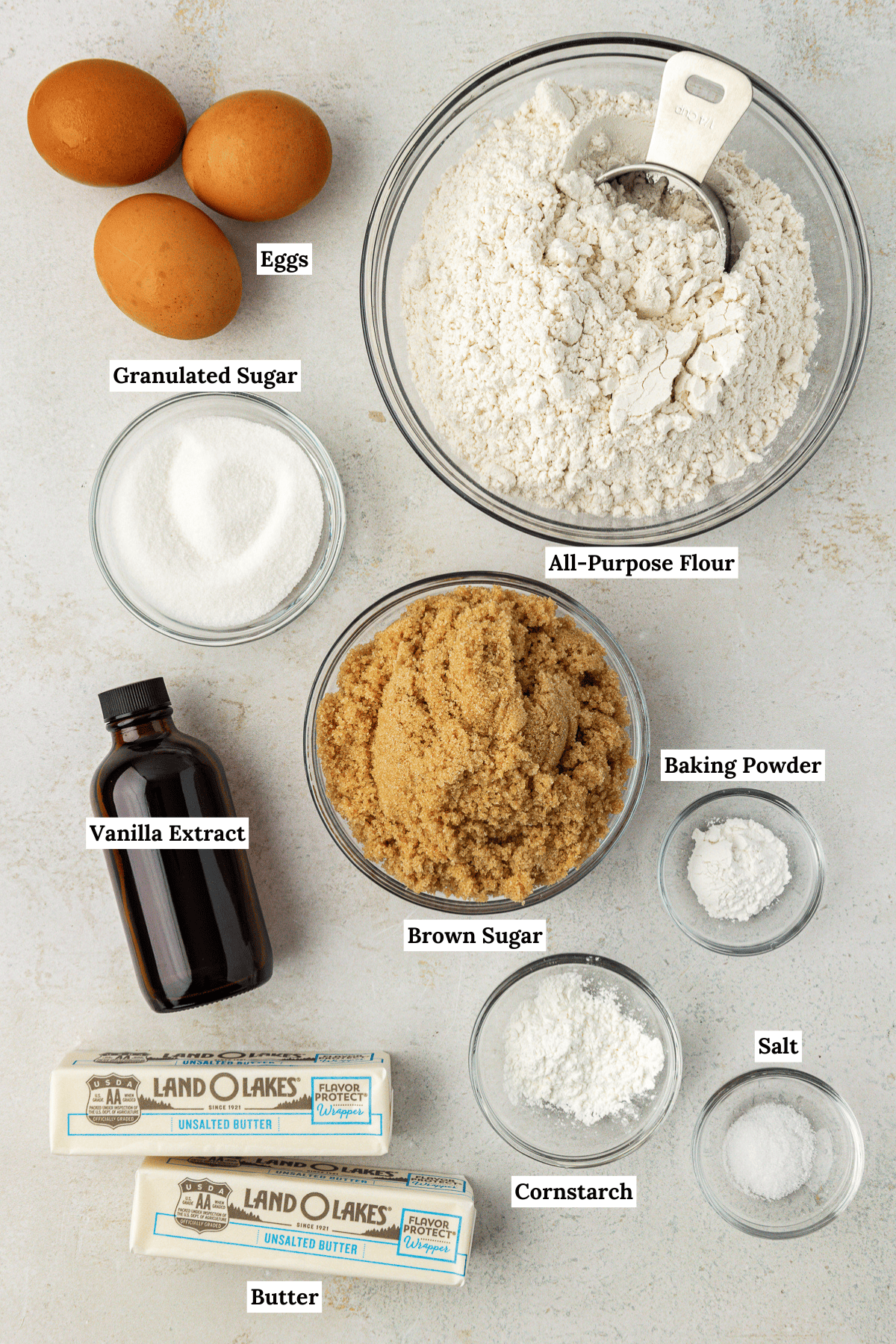 overhead view of the ingredients for blondies including eggs, all-purpose flour, granulated sugar, brown sugar, vanilla extract, baking powder, cornstarch, butter and salt