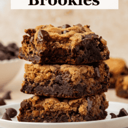 three brookies stacked in a tower on top of two small stacked white plates with chocolate chips scattered around