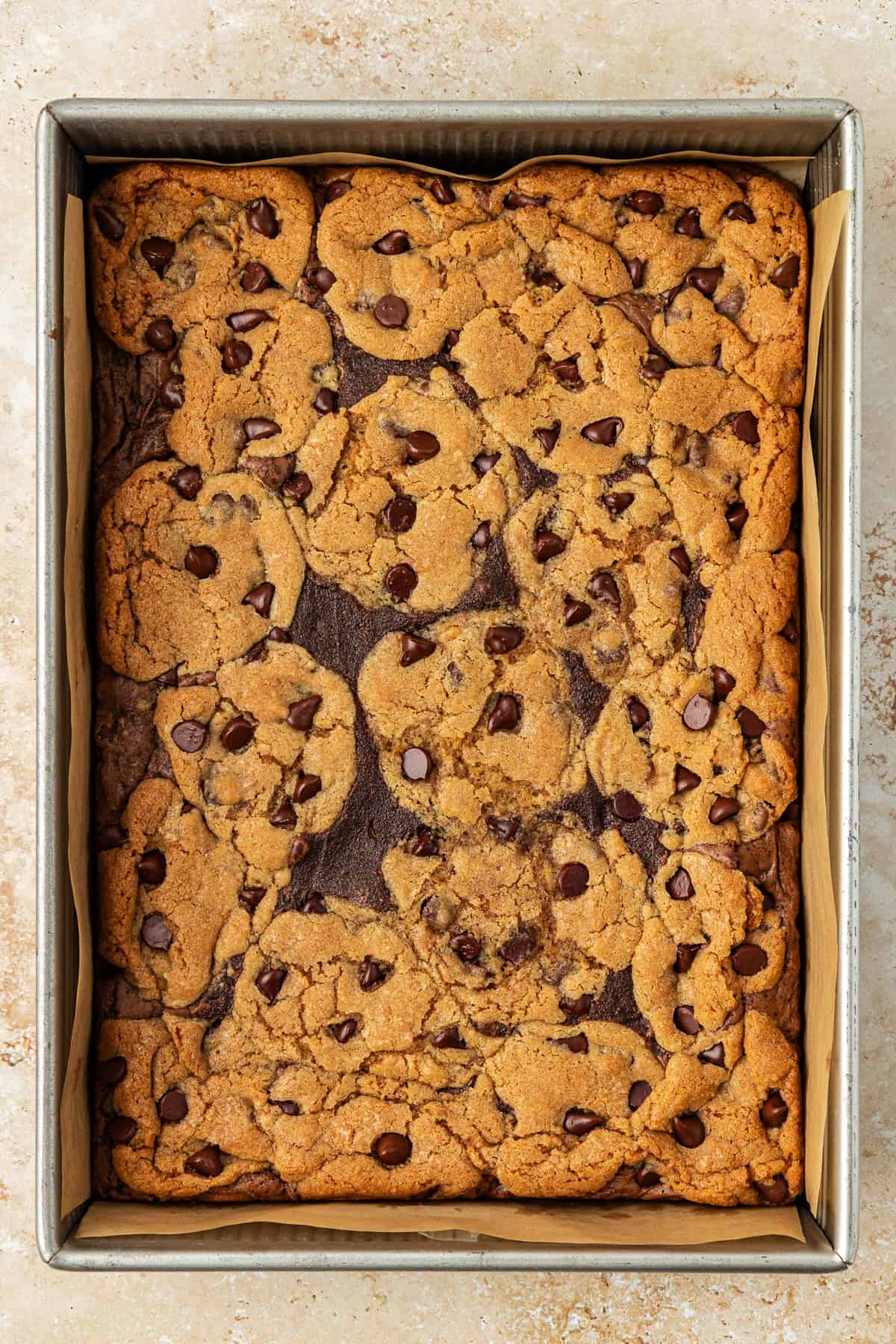 over head view of freshly baked brookies in a metal baking pan lined with parchment paper