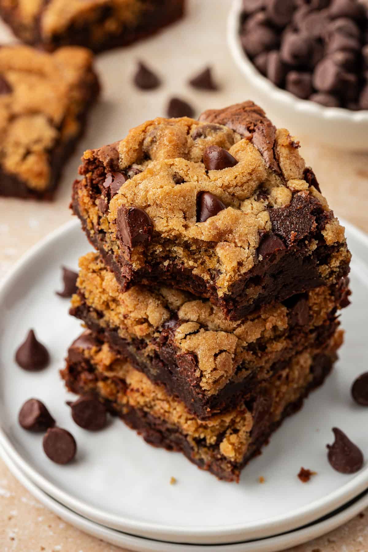 three brookies stacked in a tower on a stack of two small white plates, with more brookies and chocolate chips scattered around