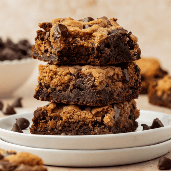 three brookies stacked in a tower on a stack of two small white plates with more brookies and chocolate chips scattered around