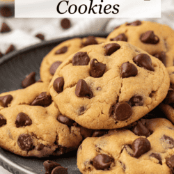 a plate full of peanut butter chocolate chip cookies on top of a white and grey striped kitchen towel with chocolate chips sprinkled around