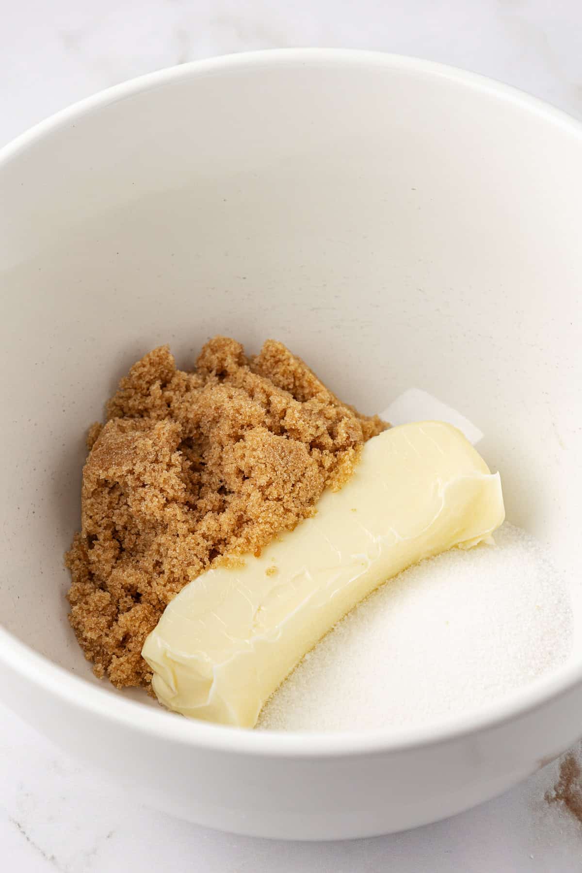 brown sugar, a stick of butter and granulated sugar in a white bowl