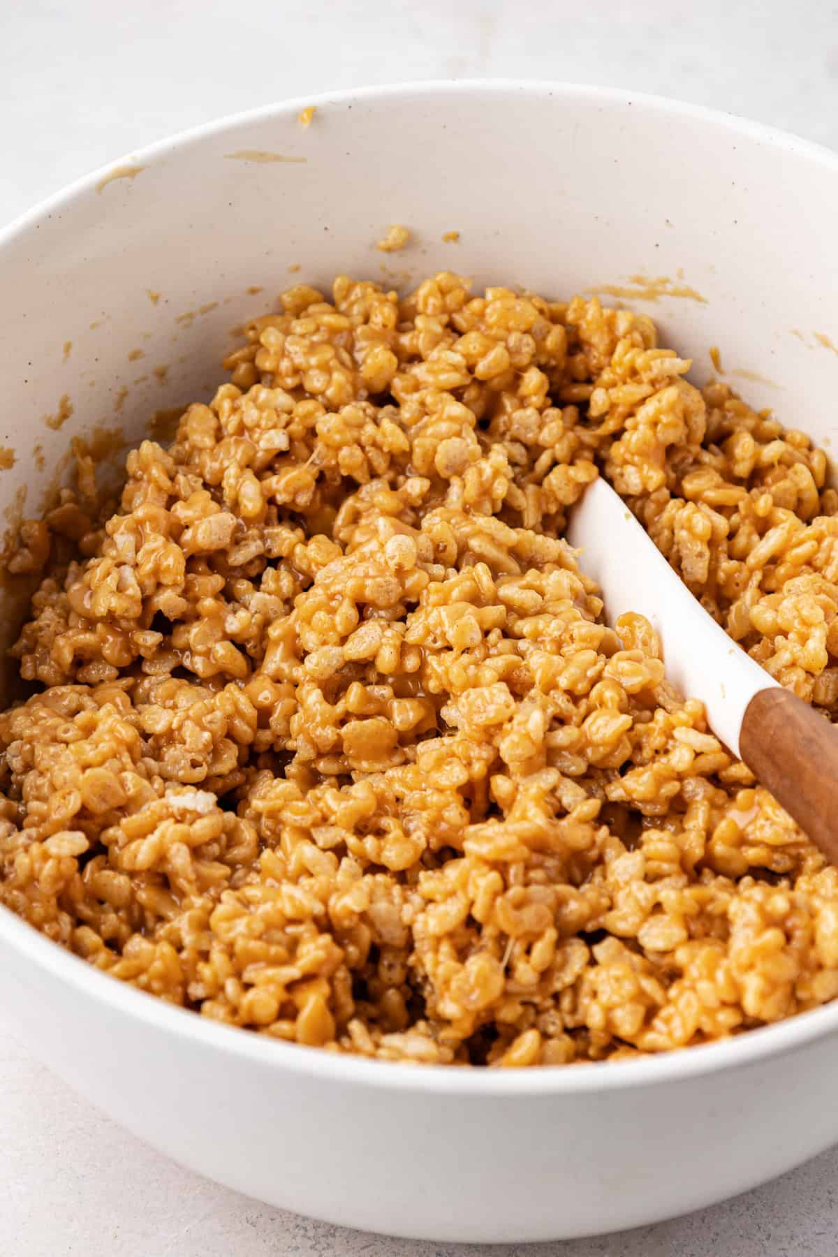 a rice krispie and peanut butter mixture in a clear glass bowl with a white spatula