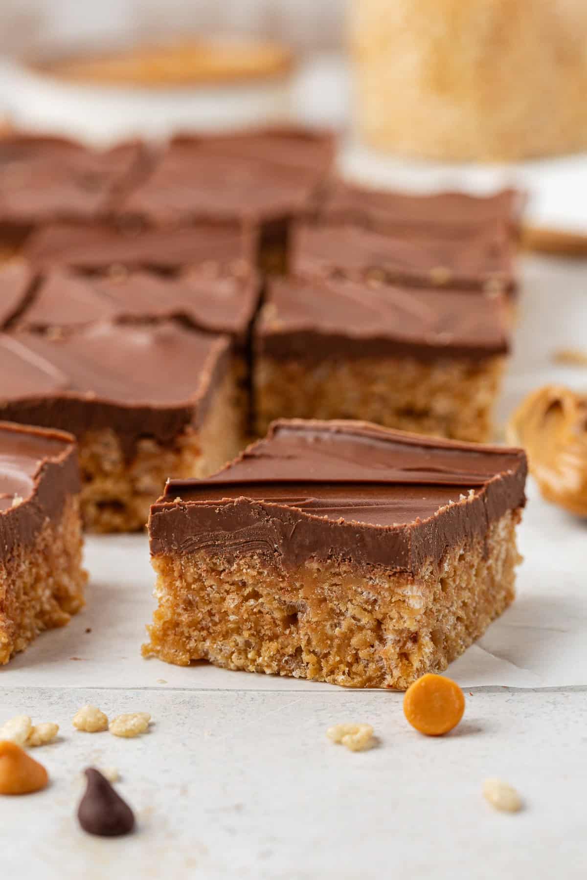 side view of scotcheroos showing their two layers with butterscotch chips, chocolate chips and rice cereal sprinkled around