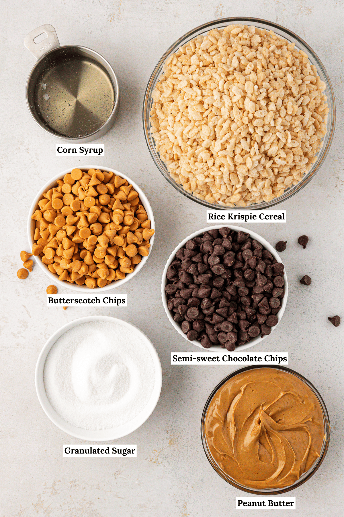 overhead view of the ingredients for scotcheroos including corn syrup, rice krispie cereal, butterscotch chips, semi-sweet chocolate chips, granulated sugar, and peanut butter