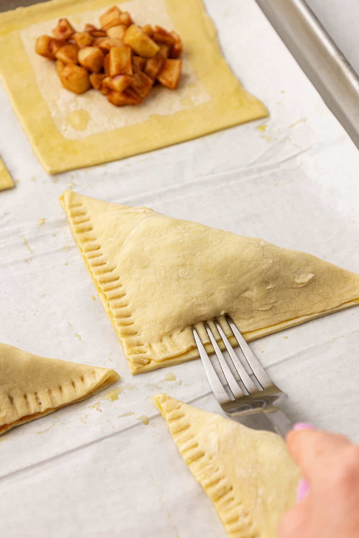 crimping the edges of apple turnovers with a fork to seal them shut