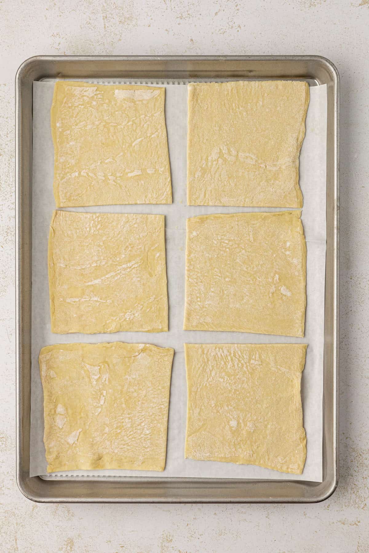 six puff pastry squares on a baking sheet lined with parchment paper