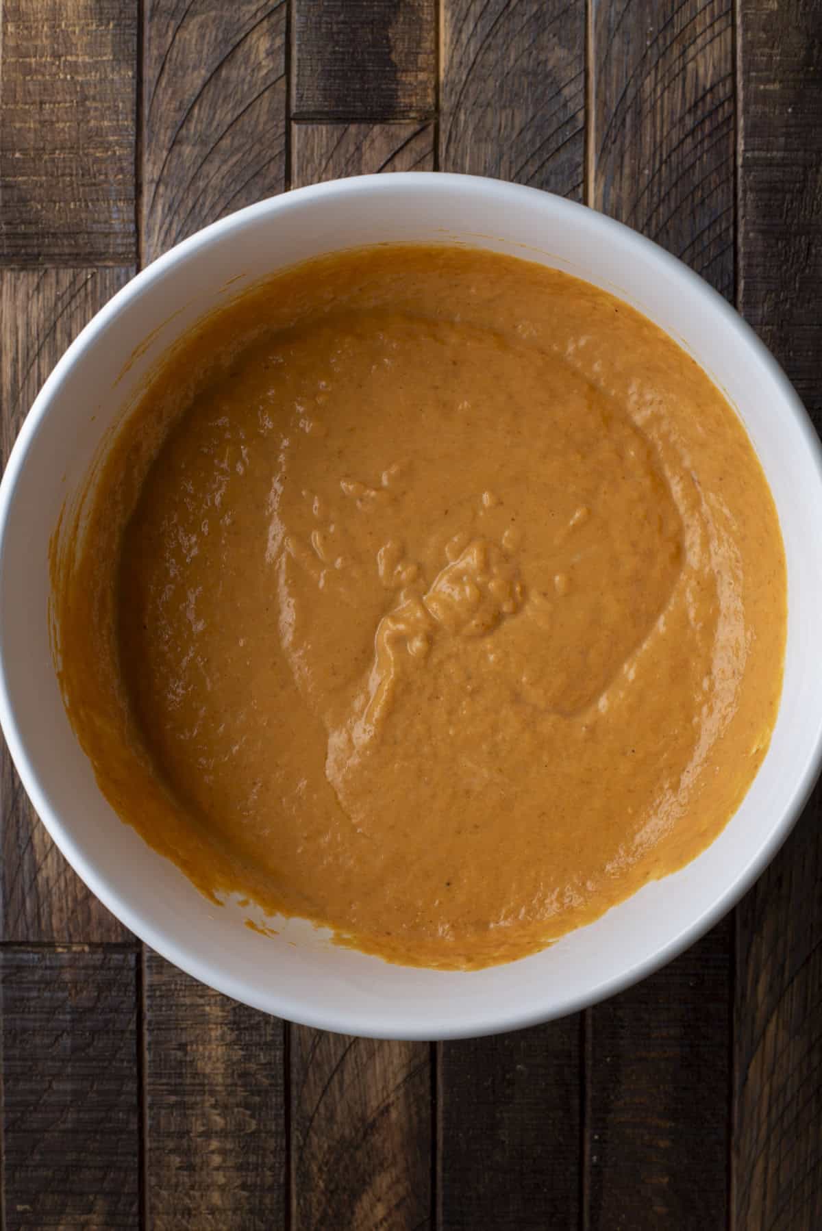 overhead view of wet ingredients for pumpkin muffins mixed in a large white bowl