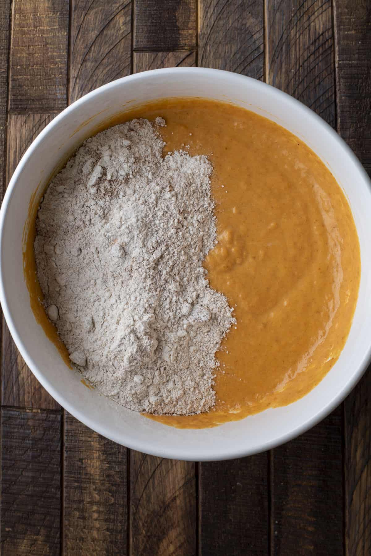 wet ingredients and dry ingredients for pumpkin muffins in a large white bowl, not combined yet