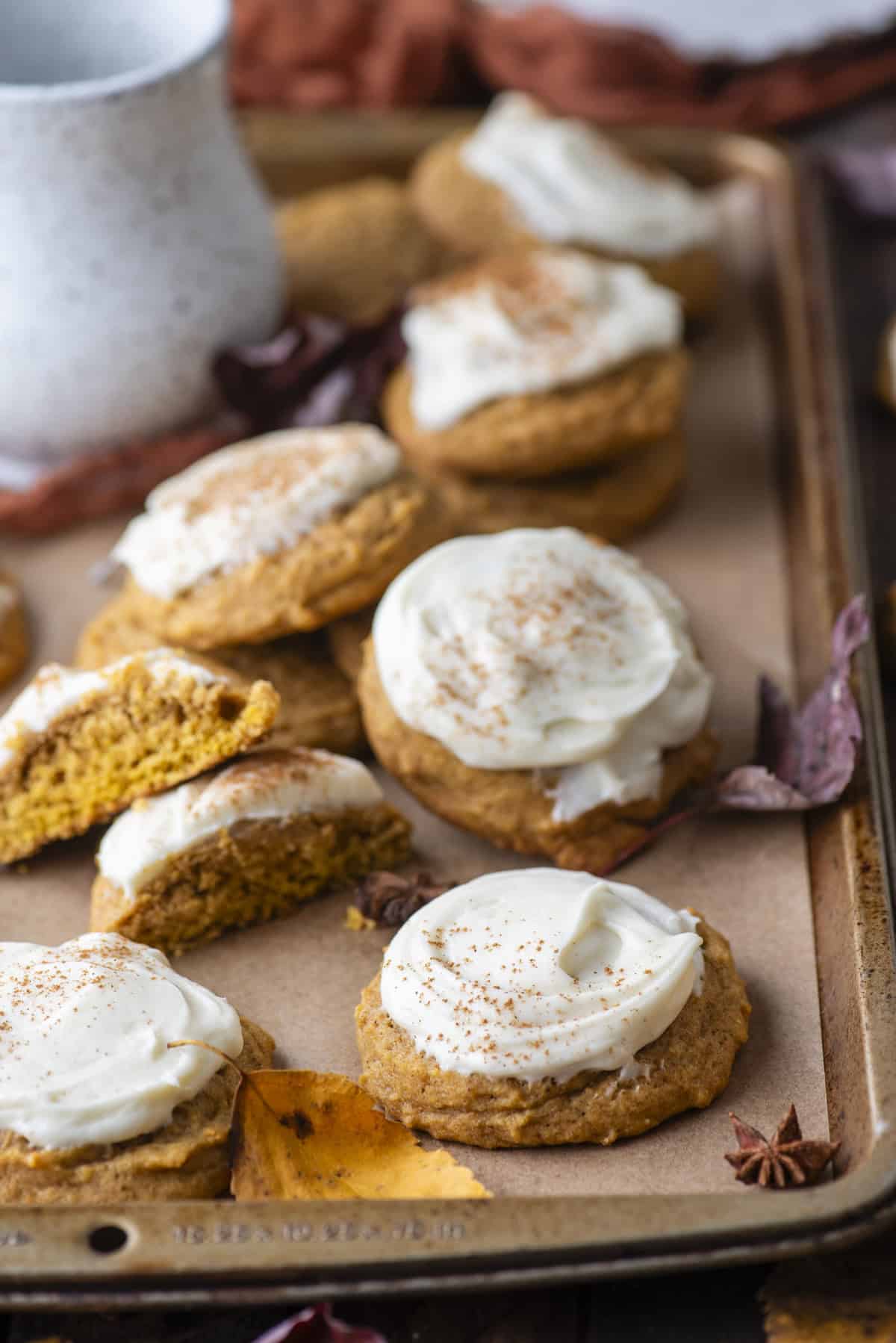 pumpkin cookies scattered around on a baking sheet surrounded by fall leaves and star anise