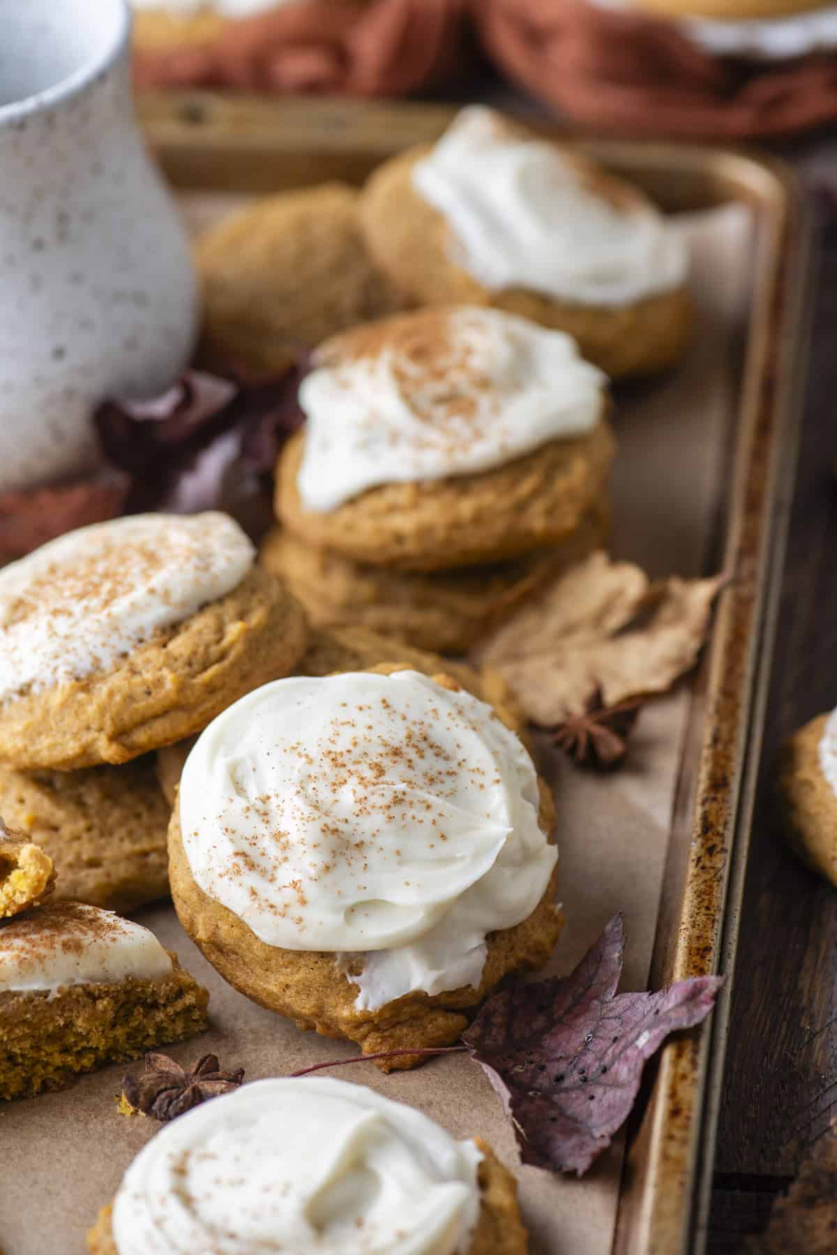 pumpkin cookies scattered around on a baking sheet surrounded by fall leaves and star anise