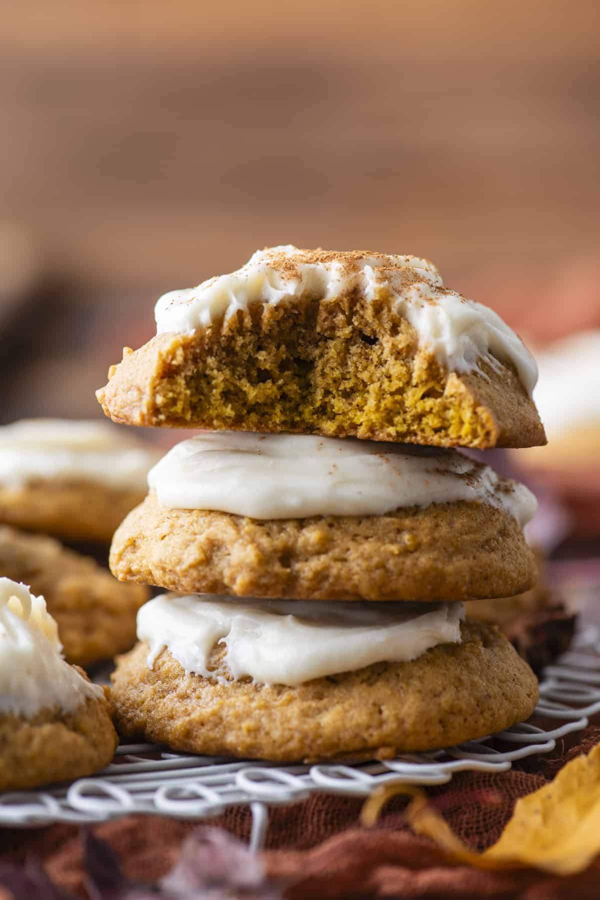 three pumpkin cookies stacked with a bite missing out of the top cookie