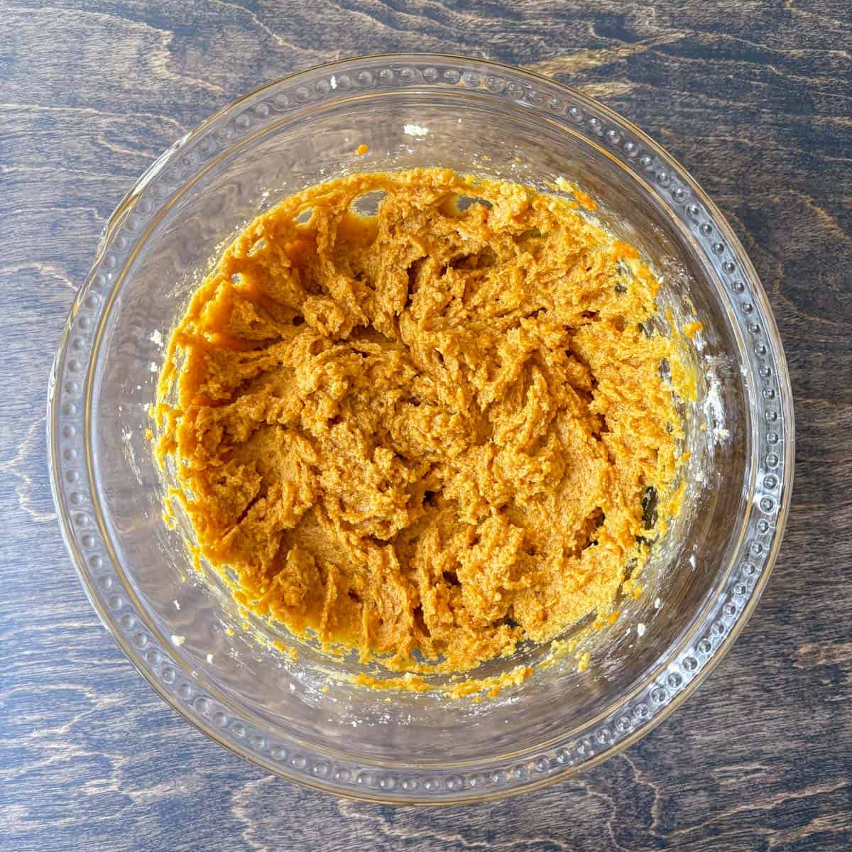 pumpkin cookie dough mixture in a clear glass bowl