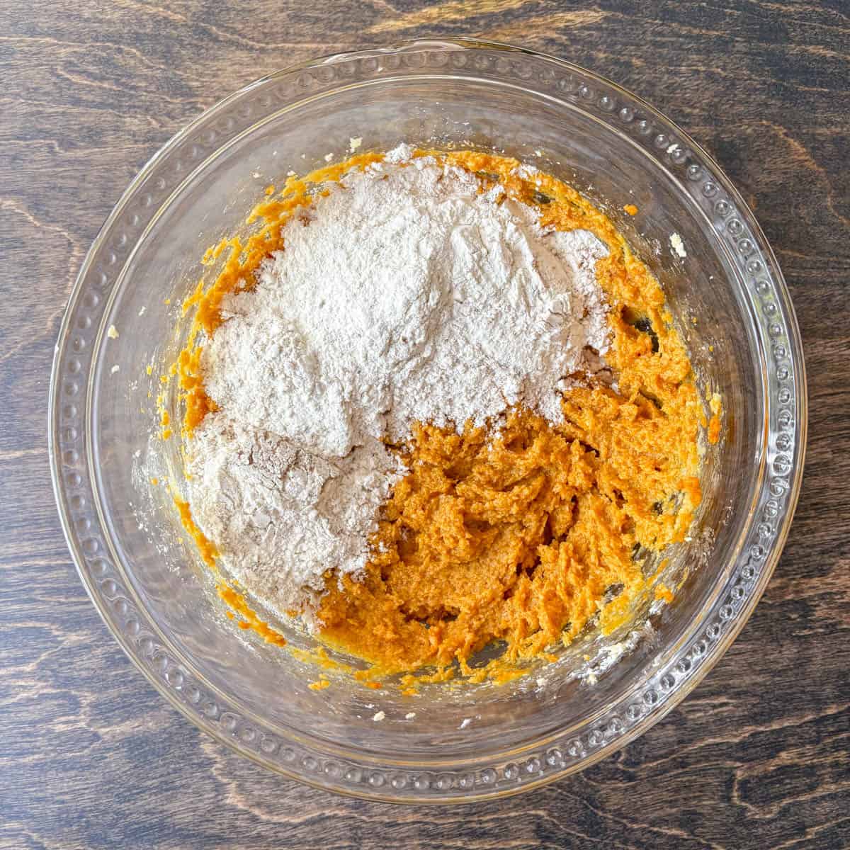 pumpkin cookie dough ingredients in a clear glass bowl, with flour mixture not yet mixed in