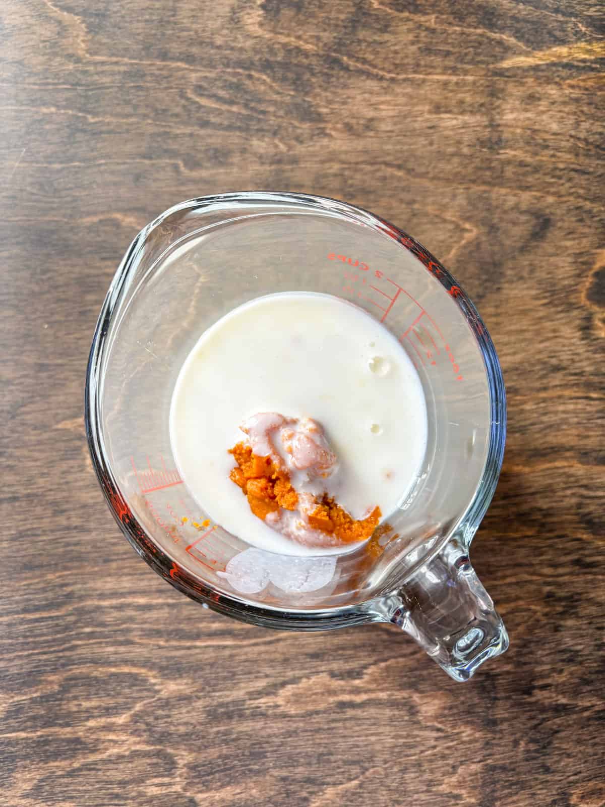 over head view of milk and pumpkin puree in a large glass measuring cup