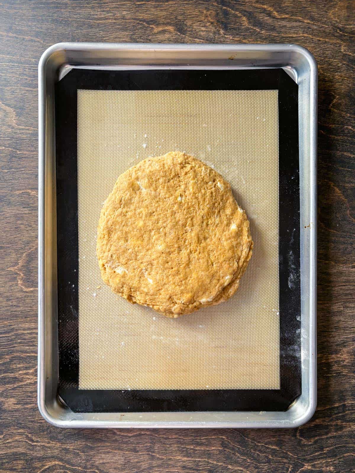 over head view of a circle of scone dough on a baking sheet lined with a silicone mat