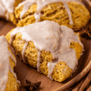 close up of a pumpkin scone on a wood plate with star anise beside it