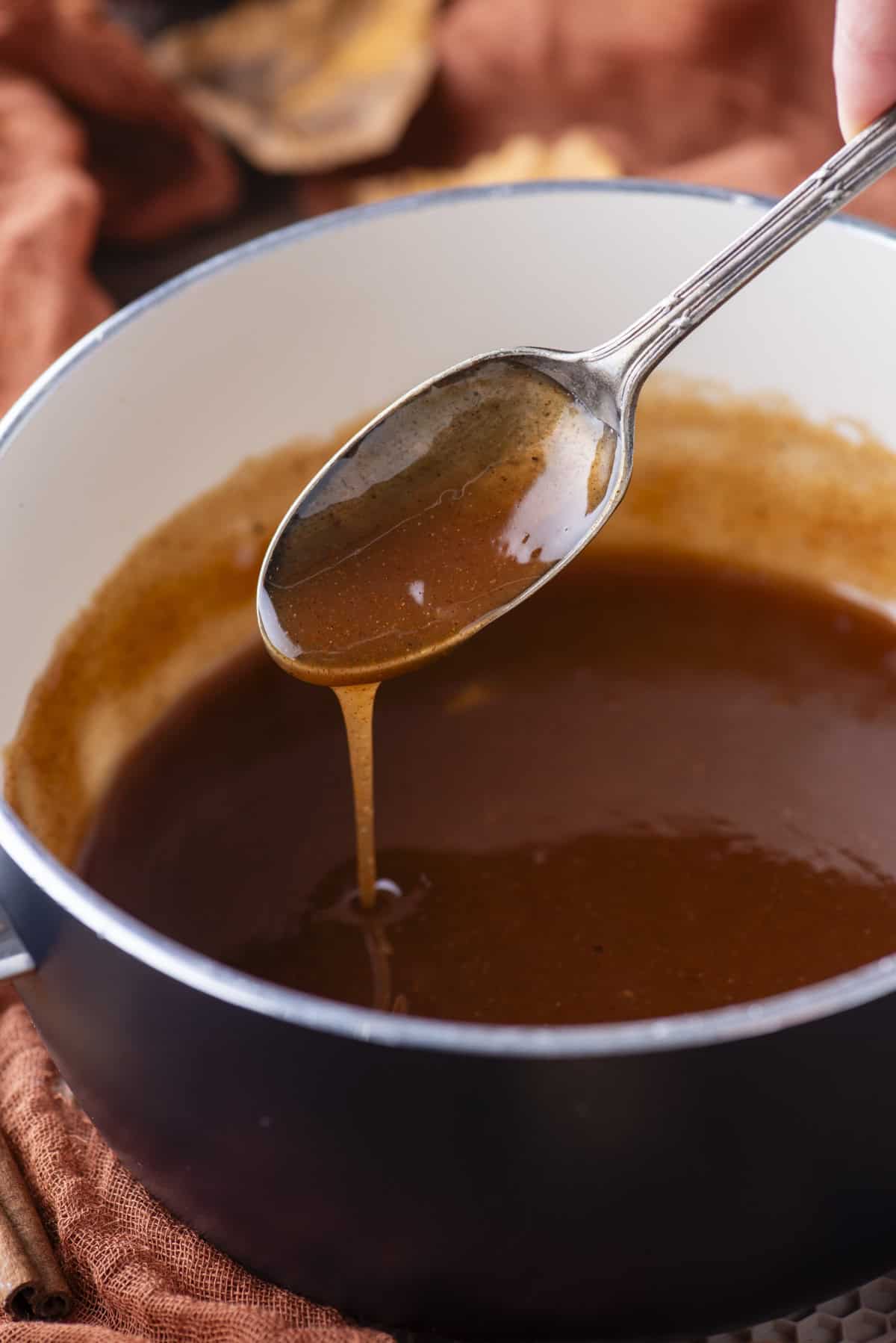 an apple filling syrup in a small saucepan, with a spoon over top with syrup drizzling down